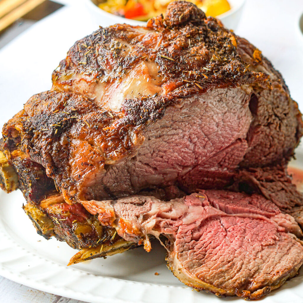 closeup of a prime rib roast sliced on a white platter