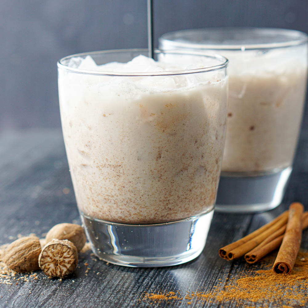 closeup of 2 glass of keto rumchata drinks with fresh nutmeg and cinnamon sticks