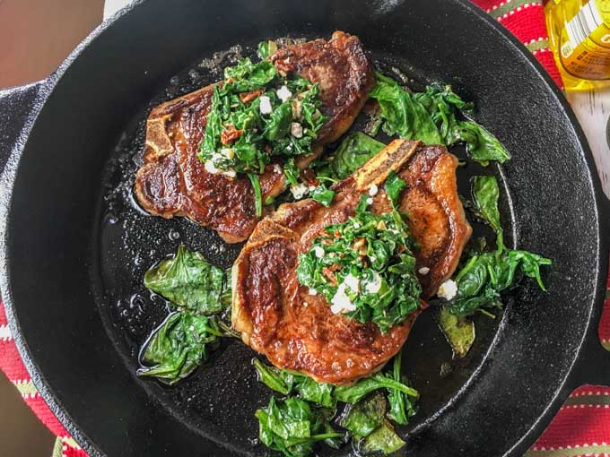 Cast iron skillet with 2 steaks and spinach.