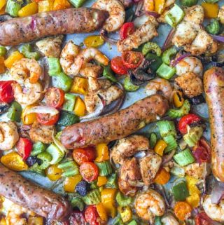 Closeup of sheet pan full of cajun chicken, shrimp, sausage and vegetables.