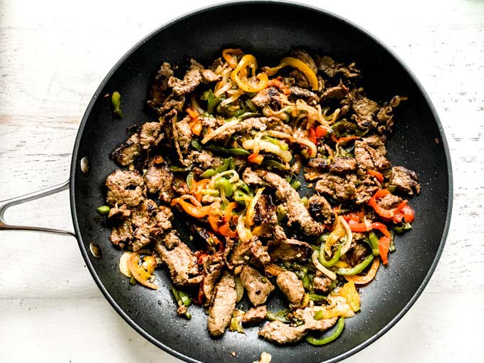 Skillet filled with steak, onions and peppers.