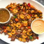 White platter with hibachi steak and shrimp with veggies and dipping sauces.