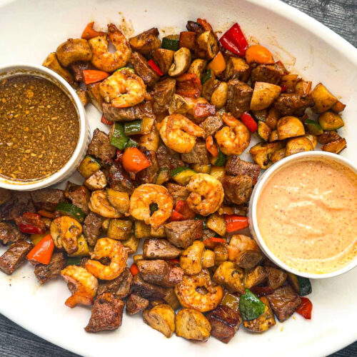 White platter with hibachi steak and shrimp with veggies and dipping sauces.