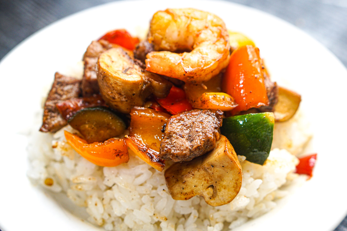 Closeup of a white plate with white rice topped with the hibachi recipe.