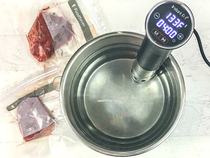 Aerial view of sous vide pot with vacuum packed steaks.