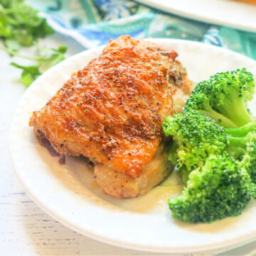 closeup of white plate with Air Fryer rotisserie chicken thighs and broccoli