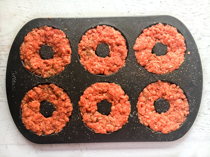 Donut pan with raw ground beef in it.