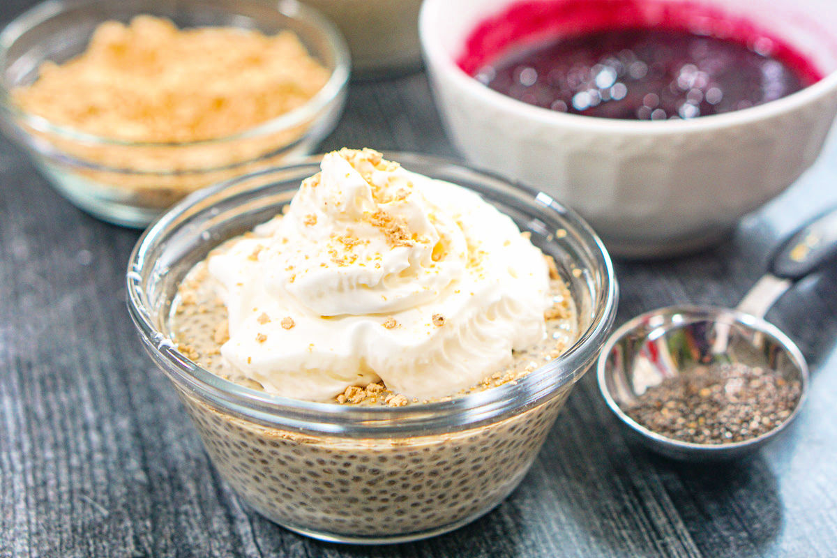 Glass dish with the finished protein dessert with whipped cream and berry sauce in the background.