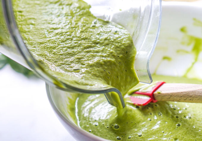 Photo of blender pitcher pouring green smoothie in bowl.