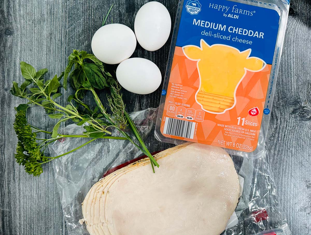 recipe ingredients - cheddar slices, eggs, fresh herbs and turkey slices