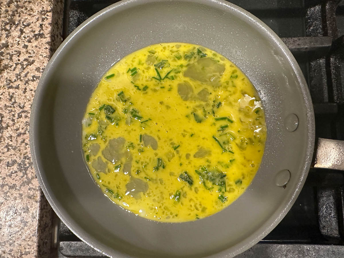 beaten egg in a skillet with fresh herbs