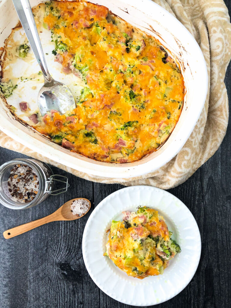 white baking dish and plate with keto broccoli and ham casserole