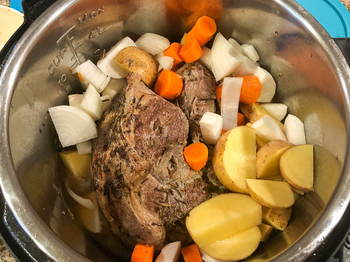 cooked lamb in a pressure cooker with raw vegetables on top