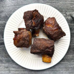 White plate with 4 bbq smoked short ribs.