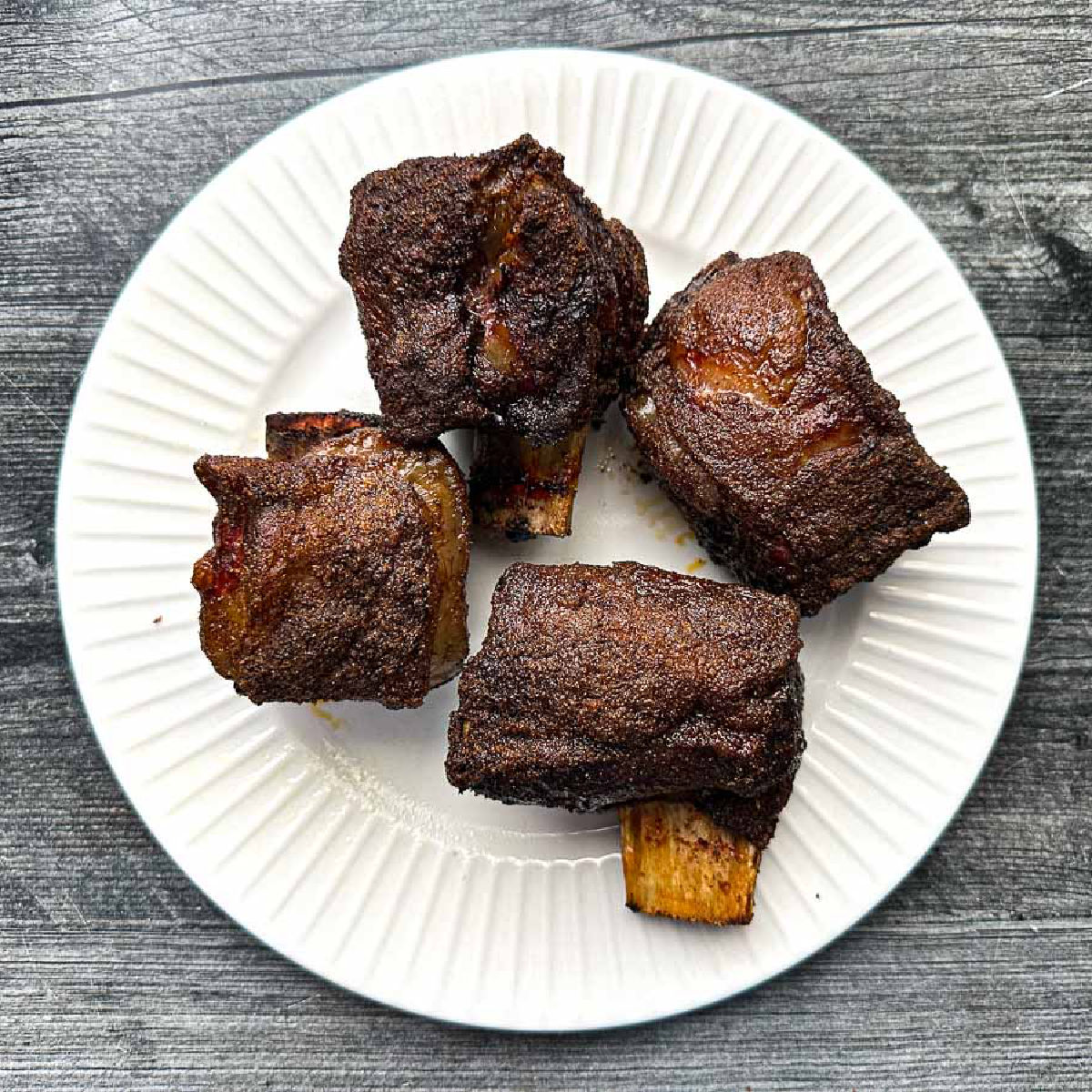 White plate with 4 bbq smoked short ribs.