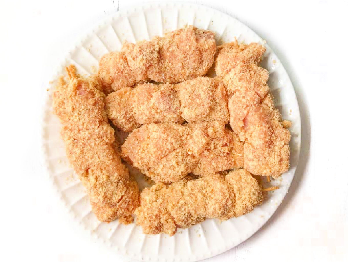 white plate with raw meat cups breaded and ready to cook