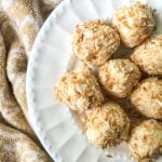 closeup of coconut protein balls on white plate with beige towel