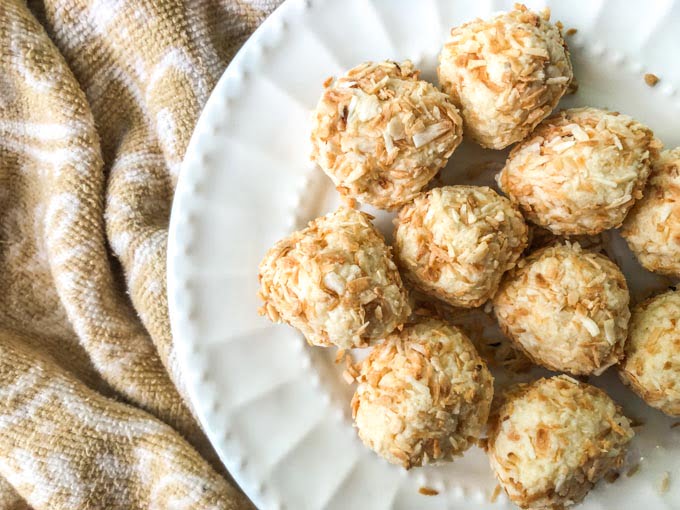 white plate with coconut cake protein bites on beige towel
