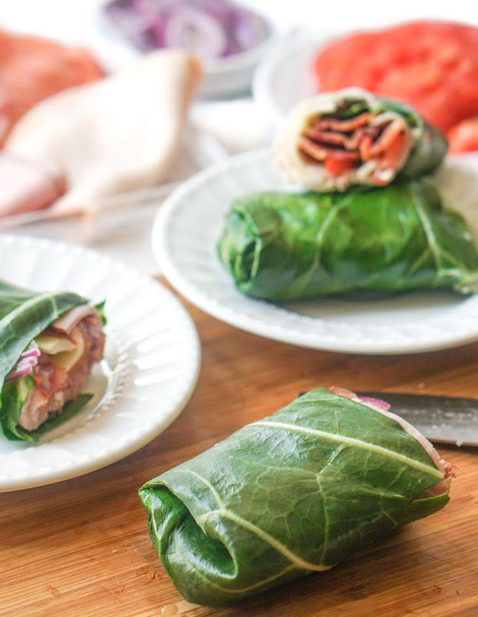 collard green  low carb sub sandwich wrap and turkey club wrap on white plates