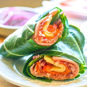 A white plate with a keto collard wrap with sub sandwich filings.