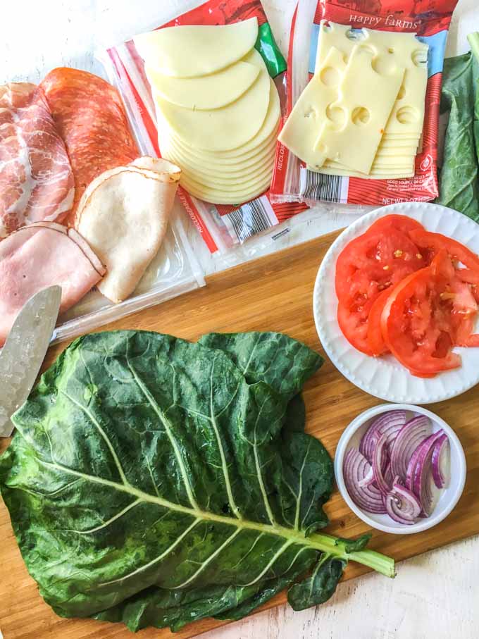 ingredients to make a collard green sub wrap on a wooden cutting board