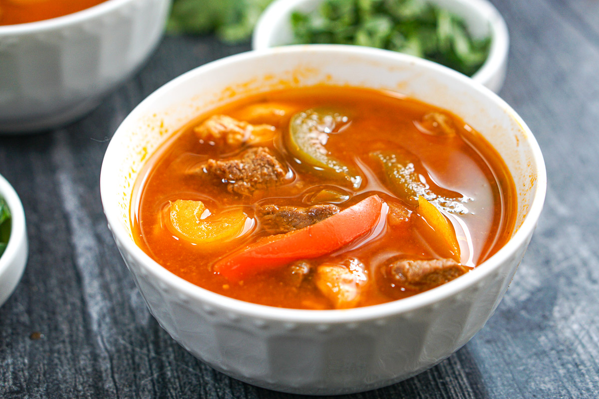 White bowl with chicken and beef Mexican soup made in the pressure cooker.