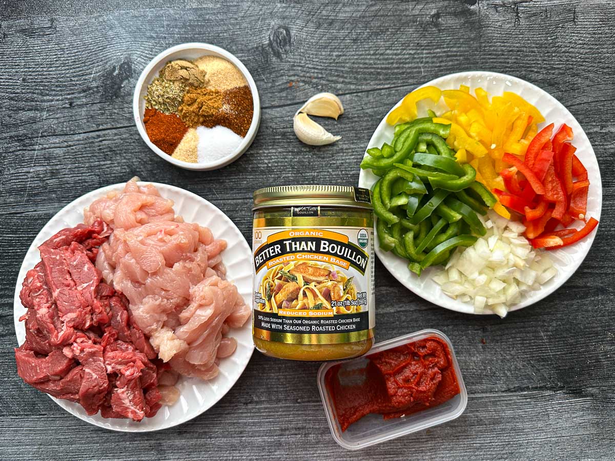 Recipe ingredients - bell peppers, onions, garlic, spices, chicken breast, sirloin beef, better than bouillon base, tomato paste and fresh garlic.