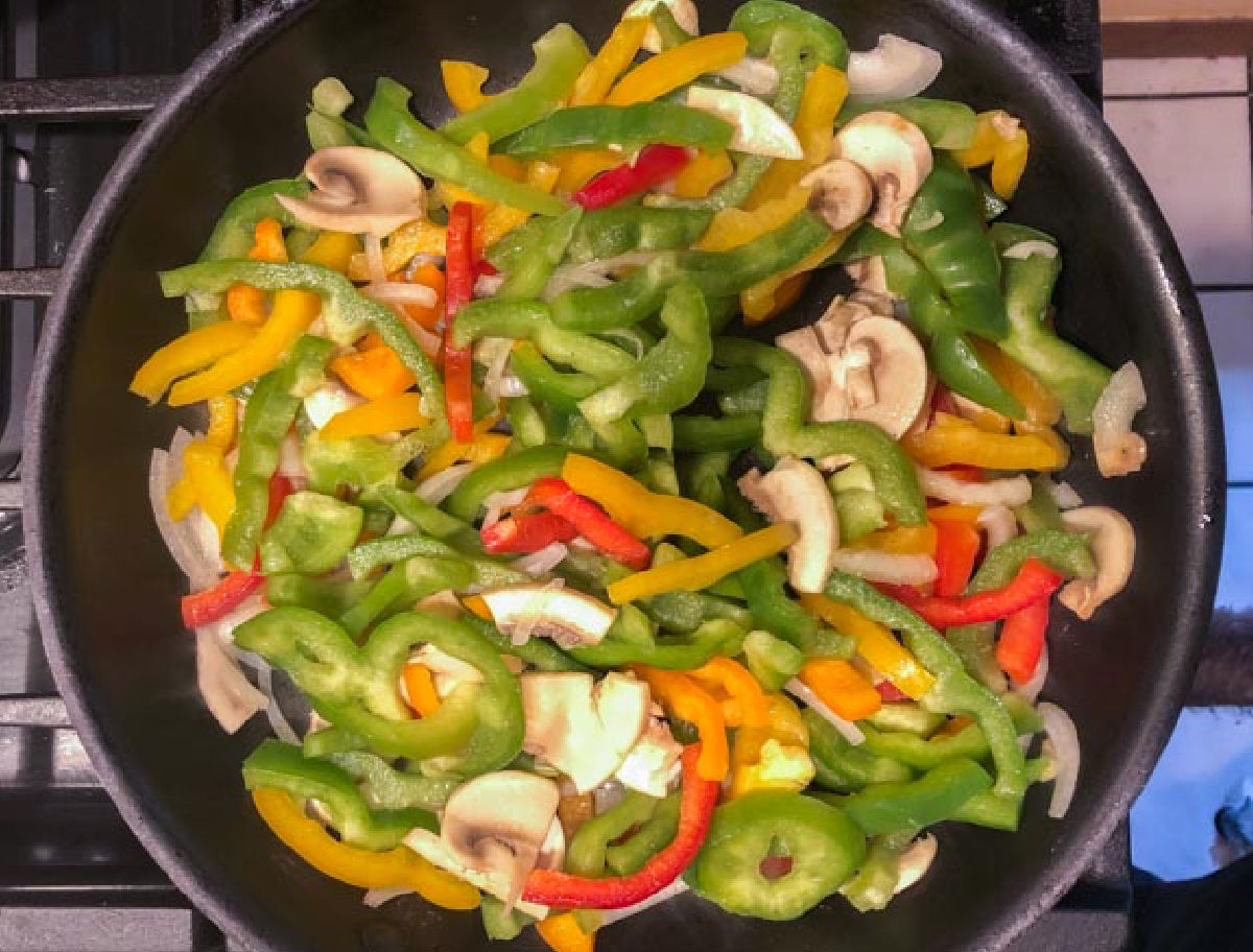 A pan with sautéed peppers, onions and mushrooms.