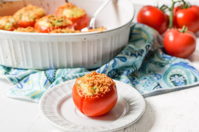 white baking dish with egg stuffed tomatoes and few tomatoes on the vine