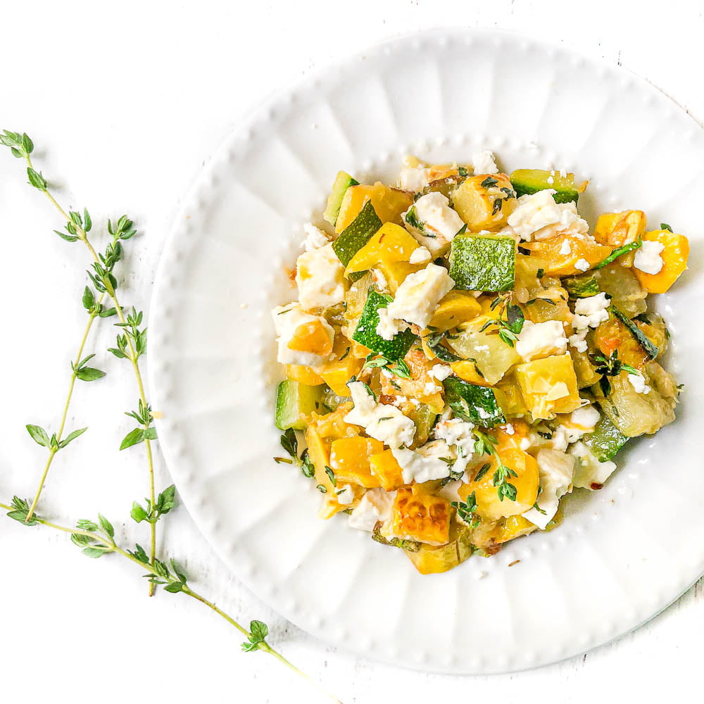 white plate with feta and zucchini side dish and sprigs of thyme