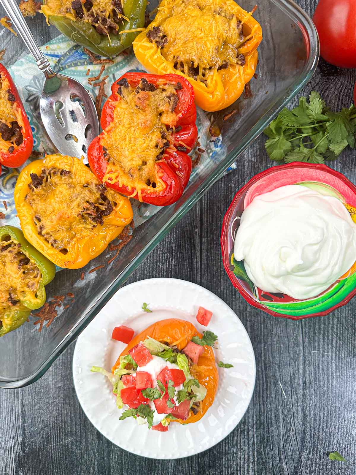 aerial view of white plate and pan of keto taco stuffed peppers with sour cream