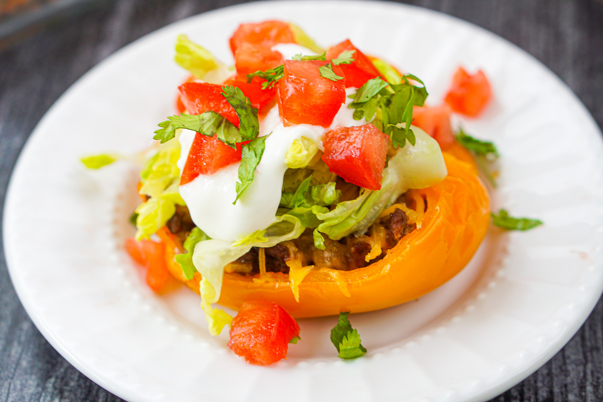 closeup of taco stuffed pepper with lettuce, tomato and sour cream