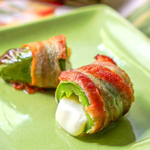 Ag reen plate with an air fryer bacon wrapped jalapenos that is cut in half.