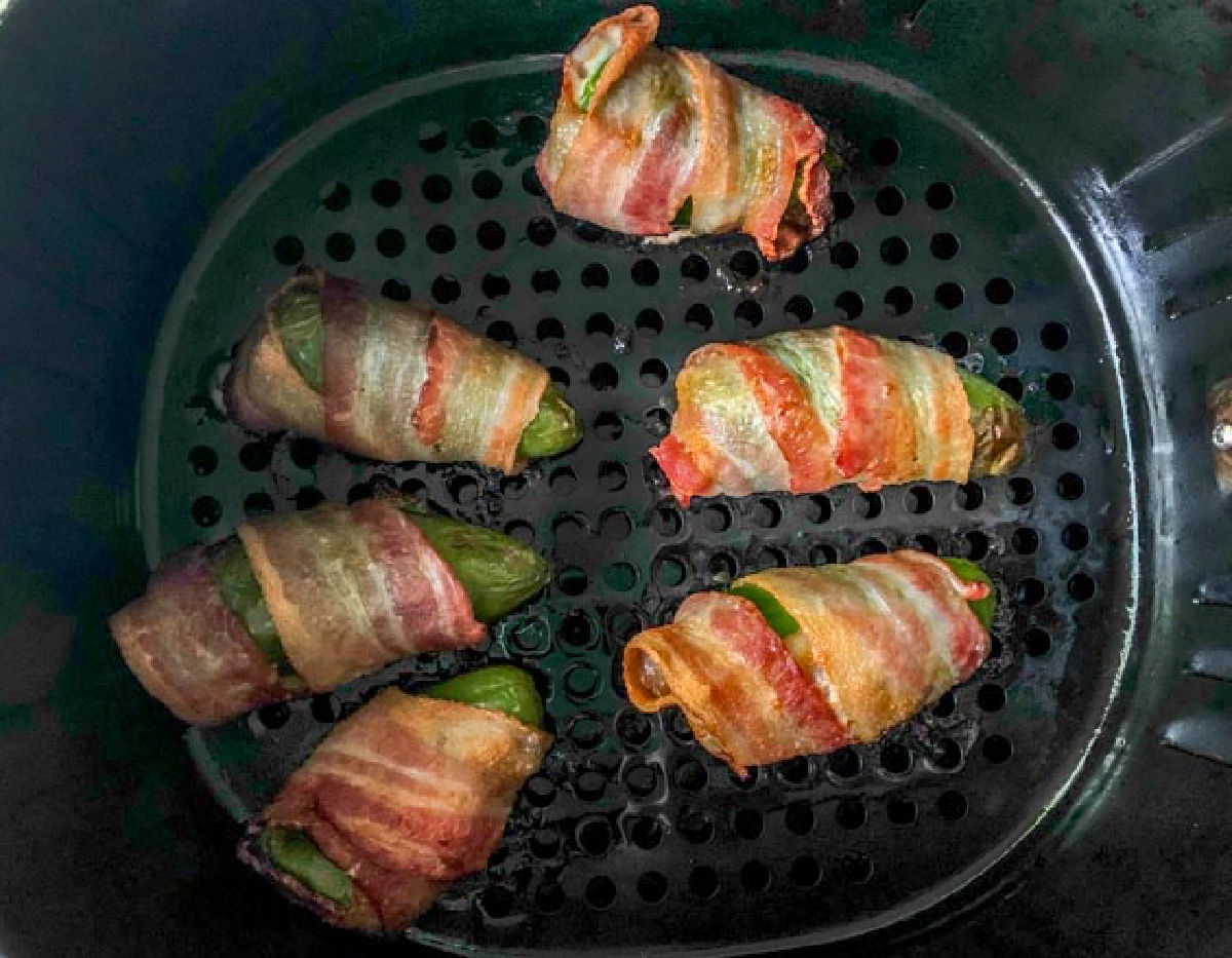 Air fryer basket with the finished jalapeno poppers.