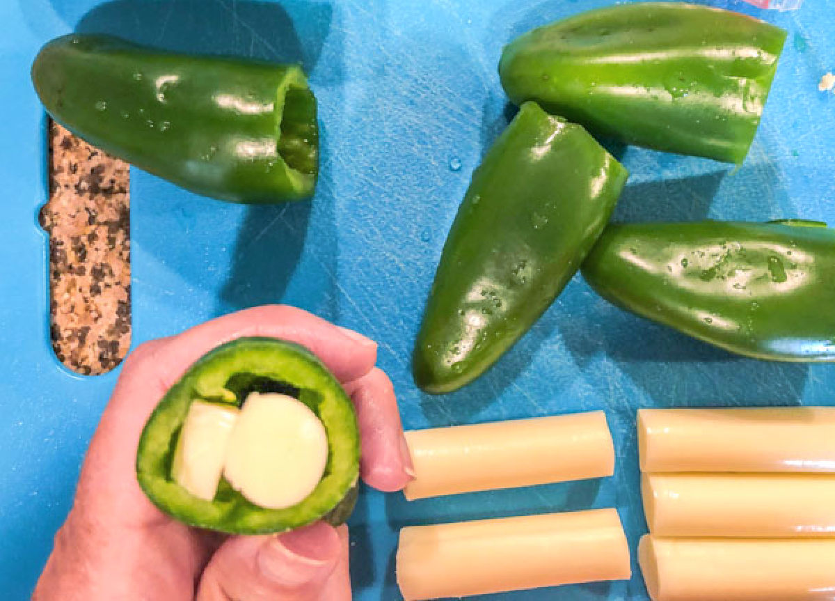 Raw peppers being stuffed with string cheese.