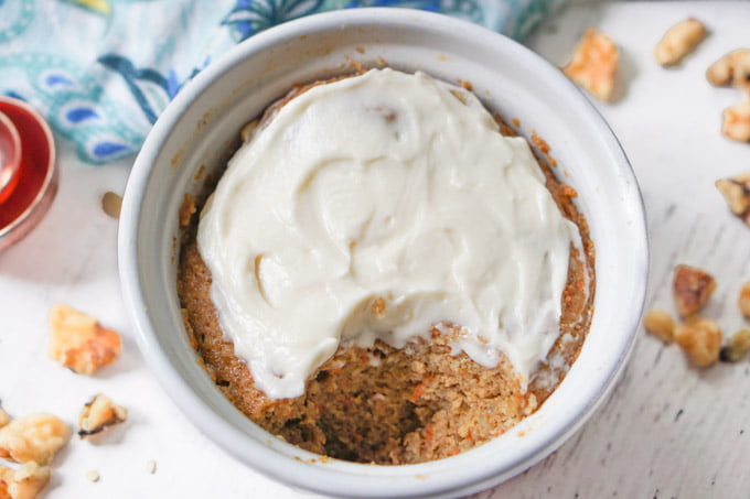white ramekin with healthy mug cake with cream cheese frosting and walnuts scattered
