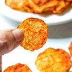 fingers holding a zucchini nacho chips with text overlay
