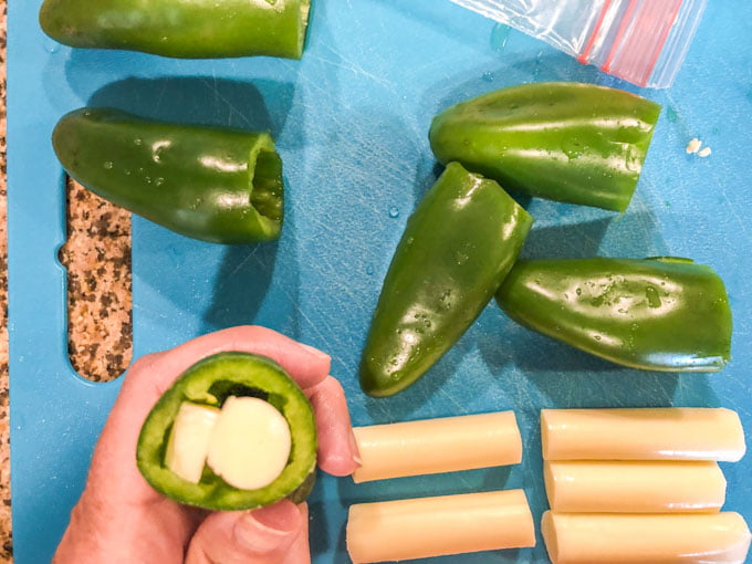 raw, cleaned jalapeno stuffed with cheesestick and blue cutting board