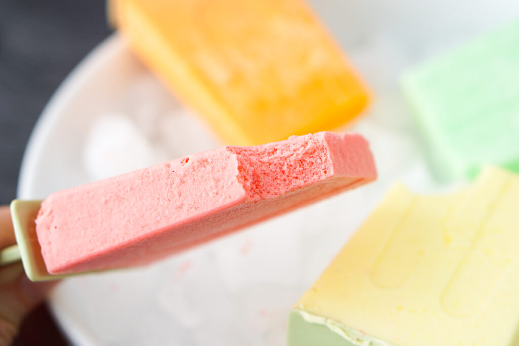 sugar free strawberry popsicle with a bite taken out