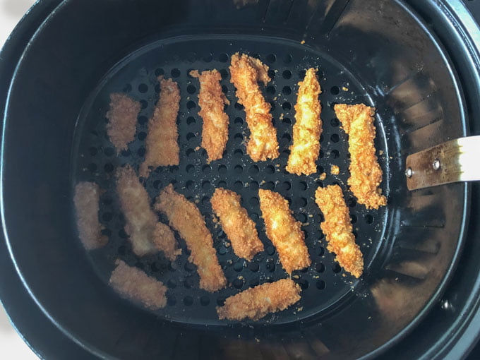 air fryer basket with fried pork chops strips done