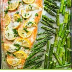 cooking sheet with a whole salmon with lemon slices and asparagus and text overlay