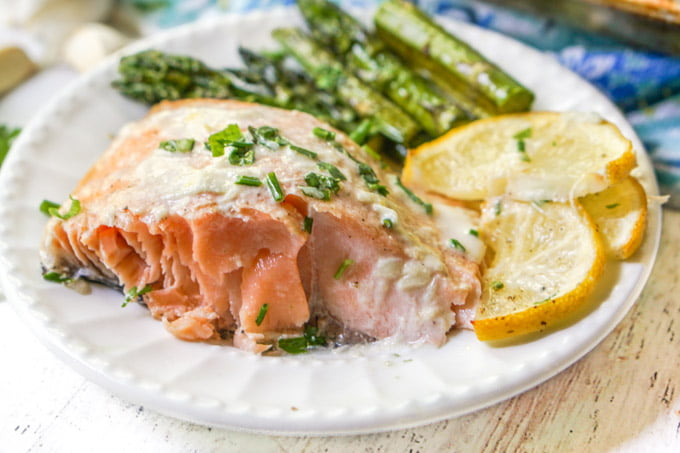 close up of salmon with asiago cream sauce, lemon slices and asparagus 