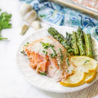 a white plate with a serving easy baked salmon with lemon slices and asparagus