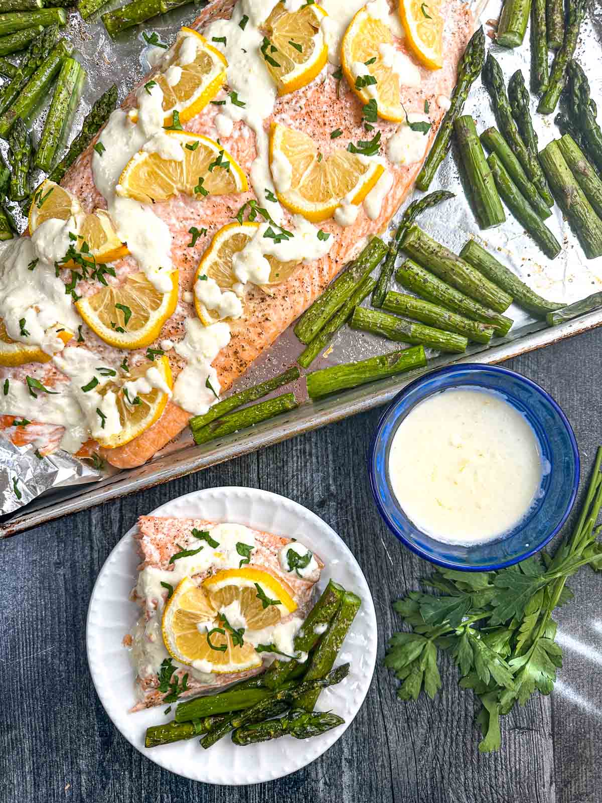 Aerial view of a sheet pan with salmon and asparagus as well as asiago cheese sauce.