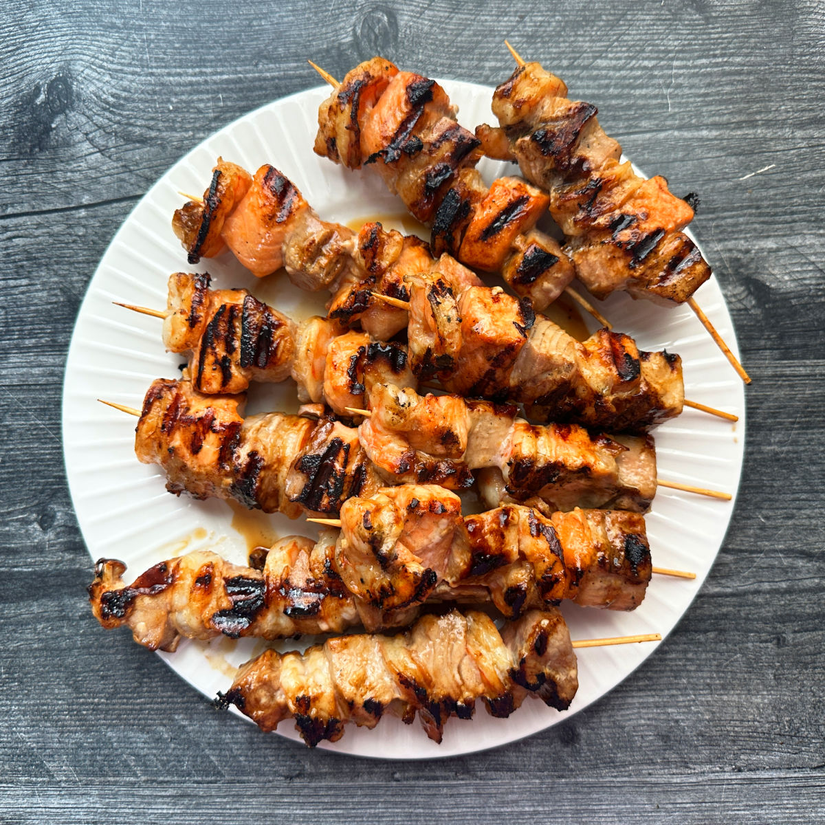 Aerial view of a white plate with marinated and grilled seafood kebabs. 