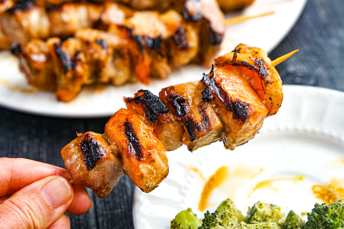 Apricot Orange Grilled Seafood Kebabs - easy, healthy and tasty dinner on the grill! Hand holding a grilled seafood skewer.