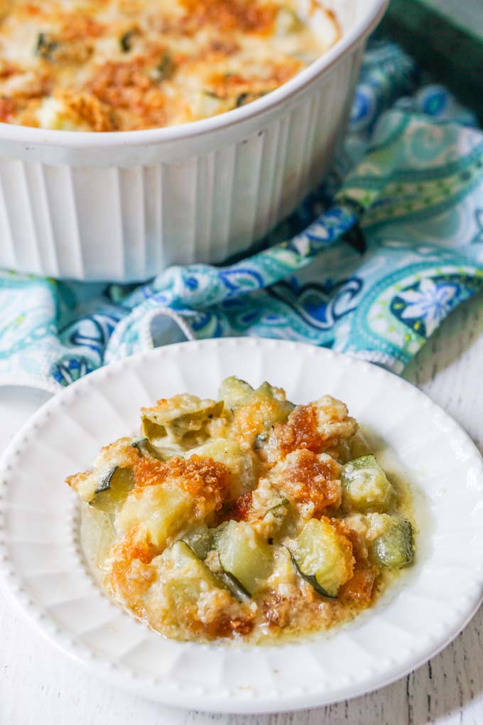 white plate with zucchini au gratin and baking dish in background