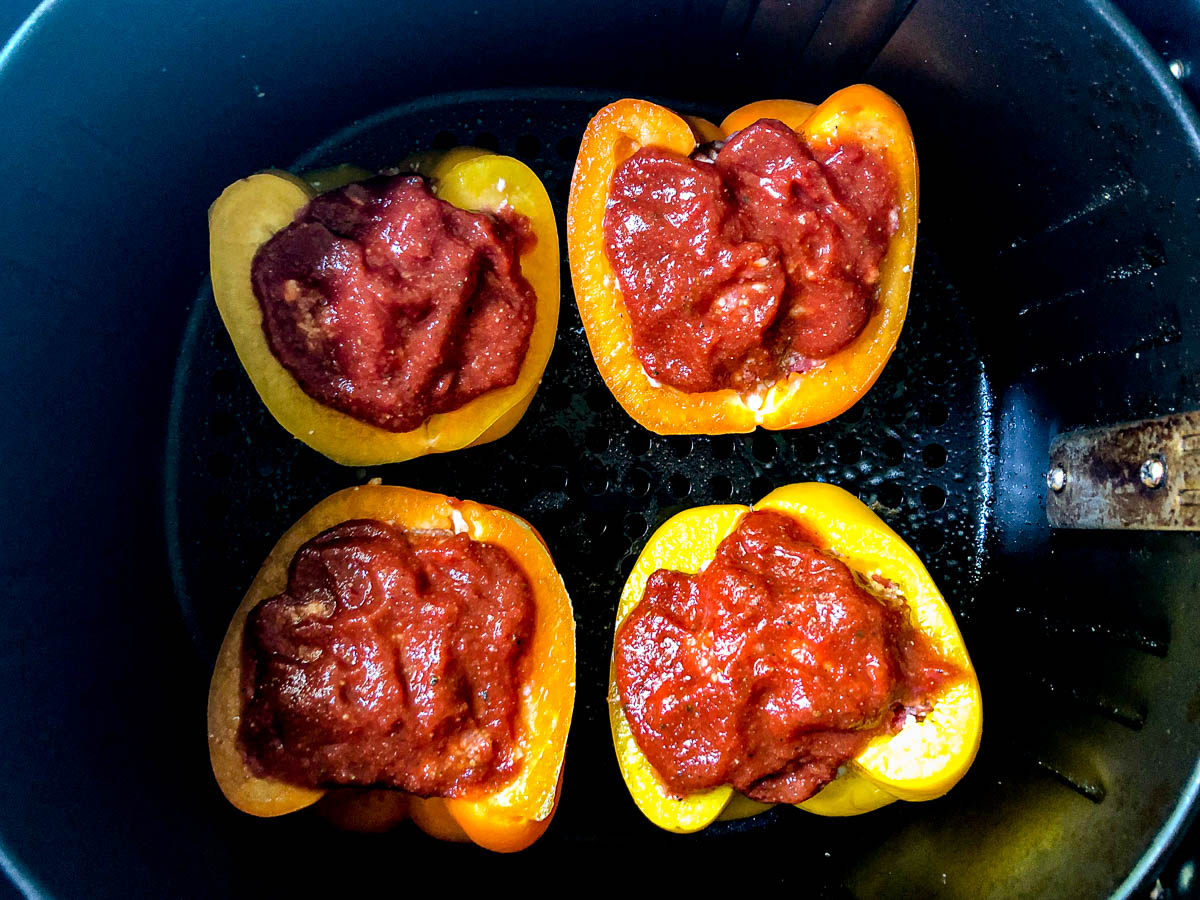air fryer basket with 4 raw keto stuffed peppers