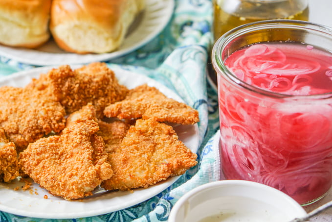 white plate with fried chicken patties and jar of red onions