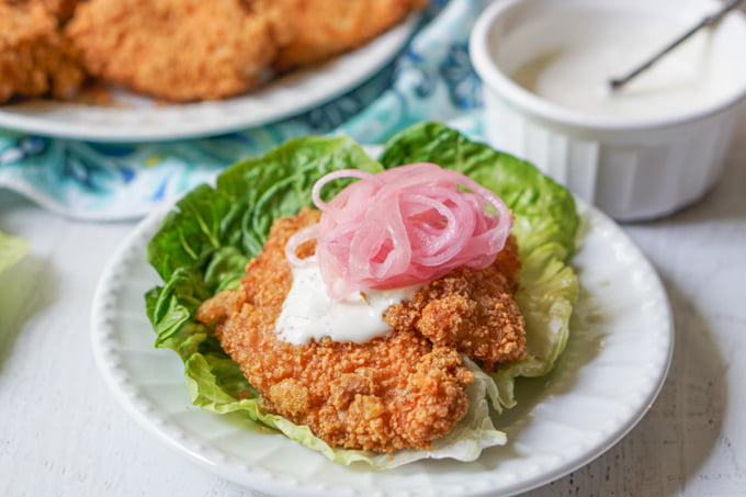 keto fried chicken sandwich using lettuce wrap on white plate